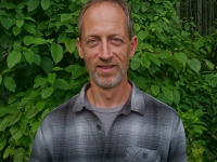 photograph of Rich Derooy - he is wearing a comfortable grey plaid shirt and smiling