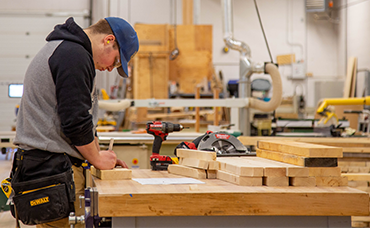 A student marks wood to be cut.